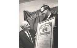 Sur la photo : Du côté gauche, le Grand Chevalier de l’époque, le Frère Romuald Lévesque, recevant d’un représentant du Conseil Suprême des Chevaliers de Colomb, la charte constitutive du Conseil 5281. La Charte originale peut encore aujourd’hui être admirée sur l’un des murs de la salle des Chevaliers sur la rue Principale dans le Vieux-Aylmer. Photo — Fonds d’archives des Chevaliers de Colomb, Conseil 5281-Aylmer